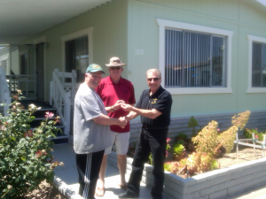 Peter K. (left) receives his keys to his manufactured home from Richard Simonian (right) of VAHP. John Yeandle (center) of Santiago Communities adds his congratulations.